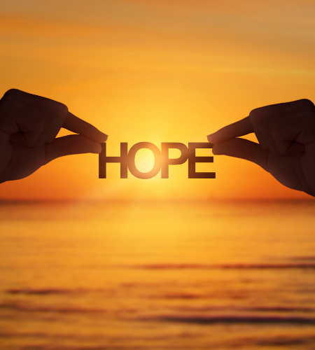 The word "HOPE" being held up in front of a sunset