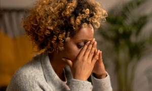 Person sitting with their face in their hands clearly looking upset.