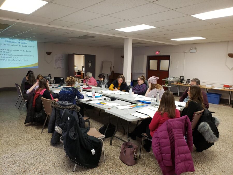 People sitting a large group table working together at a community event