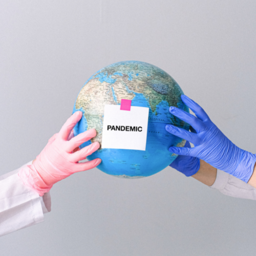 Gloved hands holding a globe with the sticky note